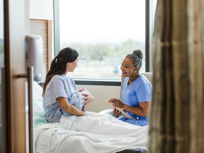 a midwife with a patient who is holding her newborn baby in a hospital setting